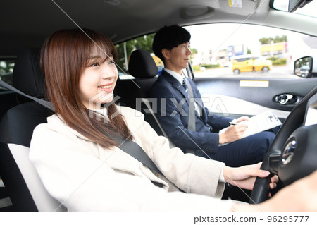 A female student taking driving lessons and an instructor watching A female student taking driving lessons and an instructor watching 96295777