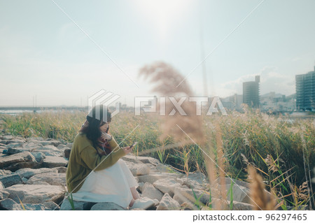 A photo of a young woman standing on the riverbed while listening to music 96297465