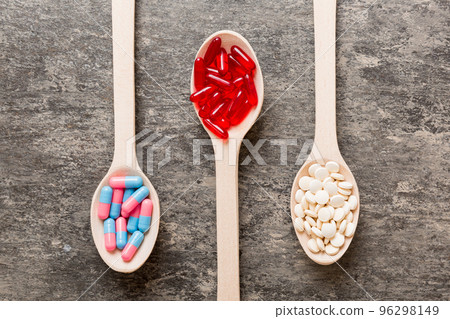 Vitamin capsules in a spoon on a colored background. Pills served as a healthy meal. Red soft gel vitamin supplement capsules on spoon Vitamin capsules in a spoon on a colored background. Pills served as a healthy meal. Red soft gel vitamin supplement capsules on spoon 96298149