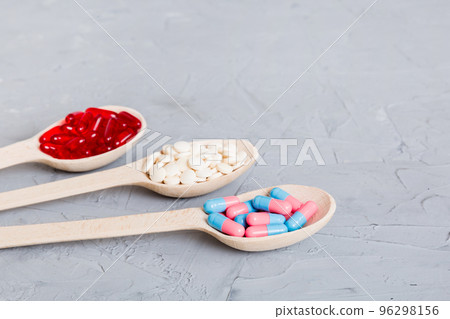 Vitamin capsules in a spoon on a colored background. Pills served as a healthy meal. Red soft gel vitamin supplement capsules on spoon Vitamin capsules in a spoon on a colored background. Pills served as a healthy meal. Red soft gel vitamin supplement capsules on spoon 96298156