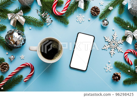 top view of smart phone with hot cup of coffee. Christmas decoration on colored background 96298425
