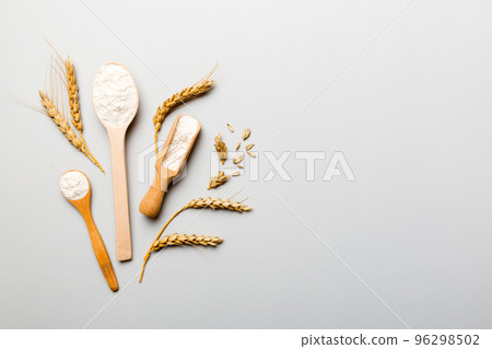 Flat lay of Wheat flour in wooden bowl with wheat spikelets on colored background. world wheat crisis Flat lay of Wheat flour in wooden bowl with wheat spikelets on colored background. world wheat crisis 96298502
