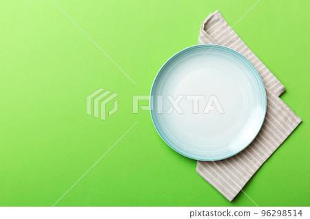 Top view on colored background empty round blue plate on tablecloth for food. Empty dish on napkin with space for your design 96298514