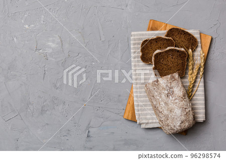 Freshly baked bread slices on cutting board against white wooden background. top view Sliced bread 96298574