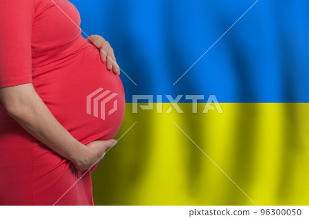 Ukrainian pregnant woman belly on flag of Ukraine background Ukrainian pregnant woman belly on flag of Ukraine background 96300050