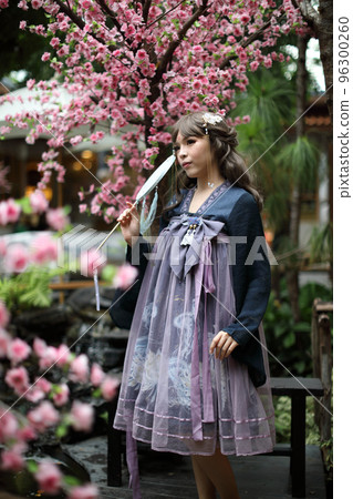 Beautiful young woman with dark blue Chinese lolita dress with Chinese garden Beautiful young woman with dark blue Chinese lolita dress with Chinese garden 96300260