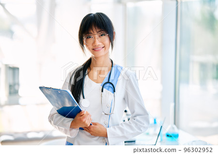 Smiling female asian doctor witn stethoscope wearing in lab coat looking to camera 96302952