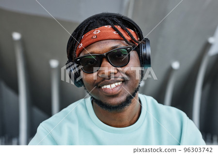 Young black man wearing headphones outdoors and smiling 96303742