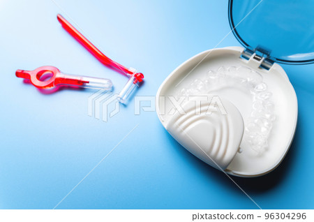 close-up, white box with plastic braces inside and red interdental brush. orthodontic care and cosmetology 96304296