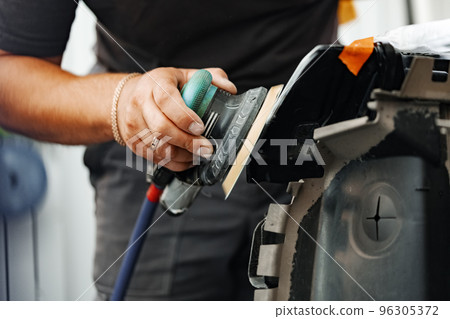 Close up of car cleaner polishing headlight with polish machine Close up of car cleaner polishing headlight with polish machine 96305372
