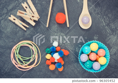 Colorful pompoms, balls and rubber erasers using for playing and development of kids motor skills 96305452