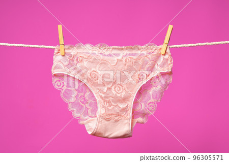 Female panties hanging on rope against pink studio background 96305571