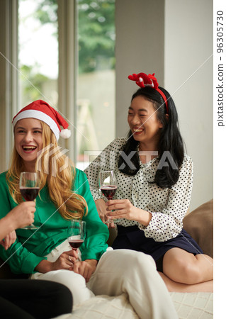 Cheerful female colleagues gathered at home after work for small Christmas party 96305730