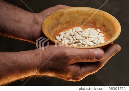 Male hands holding grains of dry kidney beans on dark background 96305731
