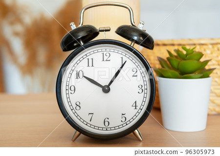 Close up of vintage alarm clock on wooden table Close up of vintage alarm clock on wooden table 96305973