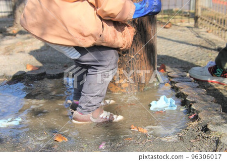 A child trying to jump relentlessly in a puddle A child trying to jump relentlessly in a puddle 96306017