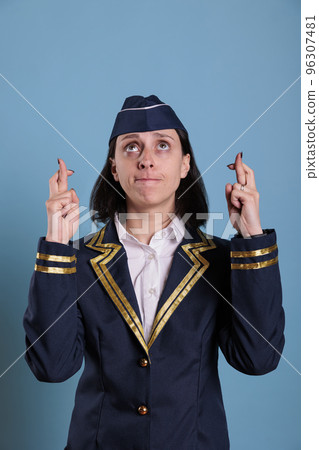 Portrait of prayer stewardess crossing fingers, looking up, praying for luck before flying. Superstitious flight attendant getting lucky, pleading for success with hopeful facial expression 96307481