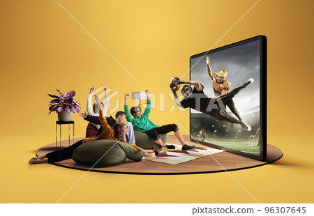 Win. Presence effect. Astonished thrilled youth, girls and boys sitting in front of huge 3D model of TV screen at home interior and watching online broadcast of american football match Win. Presence effect. Astonished thrilled youth, girls and boys sitting in front of huge 3D model of TV screen at home interior and watching online broadcast of american football match 96307645