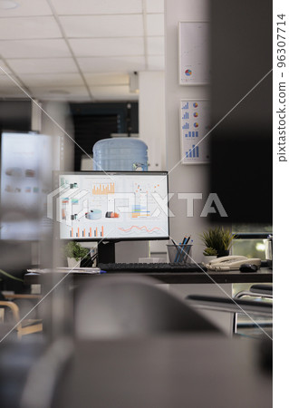 Marketing department of a company with market growth graphics and sales analysis on a desktop computer monitor. Empty office with no staff working during break time. 96307714