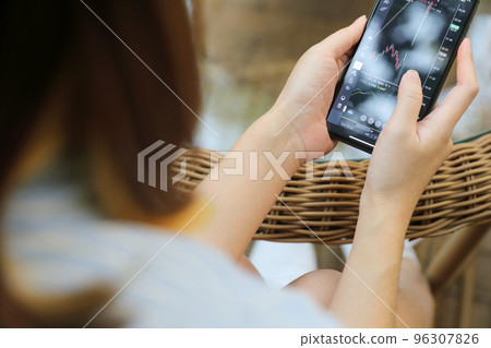 Female hand with smartphone trading stock online in coffee shop , Business concept Female hand with smartphone trading stock online in coffee shop , Business concept 96307826