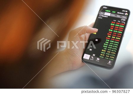 Female hand with smartphone trading stock online in coffee shop , Business concept Female hand with smartphone trading stock online in coffee shop , Business concept 96307827
