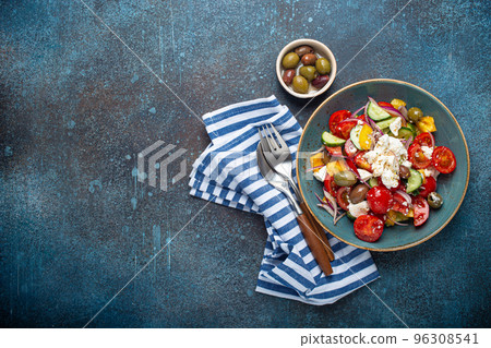 Greek salad with feta cheese, vegetables, olives in blue bowl on concrete background Greek salad with feta cheese, vegetables, olives in blue bowl on concrete background 96308541