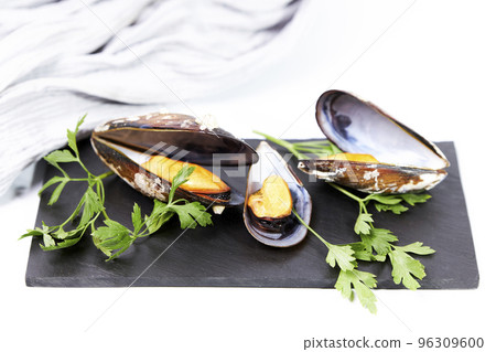 Steamed mussels with parsley on a slate next to a cloth on a white background Steamed mussels with parsley on a slate next to a cloth on a white background 96309600