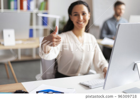 Happy millennial european woman manager working at computer, show thumb up sign in modern office interior Happy millennial european woman manager working at computer, show thumb up sign in modern office interior 96309718