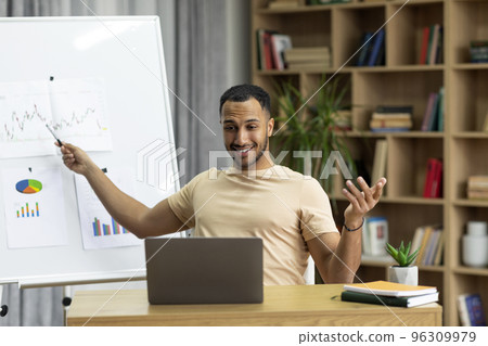 Happy arab man teaching online talking to laptop webcamera, having video call lecture with student, sitting at workplace 96309979