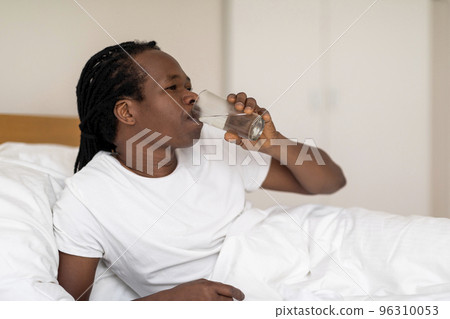 Thirsty Black Man Drinking Water From Glass While Resting In Bed 96310053