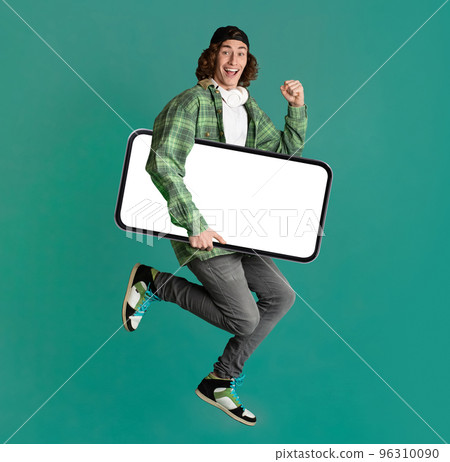 Excited Hipster Guy Jumping With Big Blank Smartphone In Hands 96310090