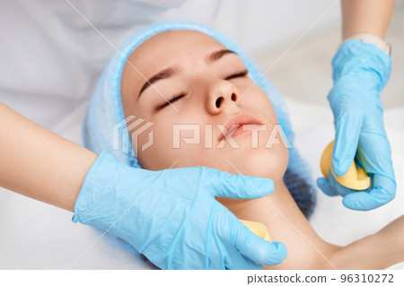 beautician cleanses skin of beautiful woman with a sponge. 96310272