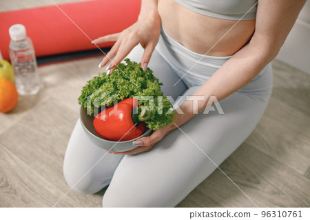Fit woman with lots of healthy fresh food at home. Cropped view of woman wearing grey leggins. Concept of losing weight, sports and healthy eating. 96310761