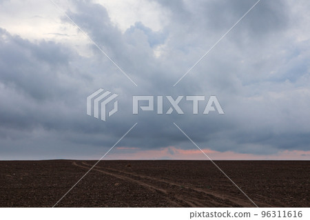 Autumn cloudy cultivated rural field and dirt road 96311616