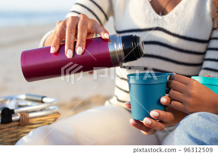 Close-up of woman pouring tea from thermos 96312509