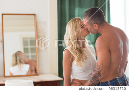 Cute woman and man standing in bedroom in morning and kissing Cute woman and man standing in bedroom in morning and kissing 96312710