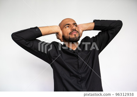 Portrait of confident young man covering ears and looking away 96312938