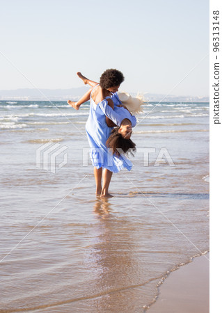 Jolly mother and daughter playing on beach 96313148