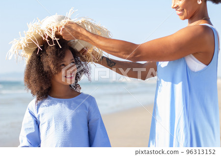 Smiling mother and daughter spending time on beach 96313152