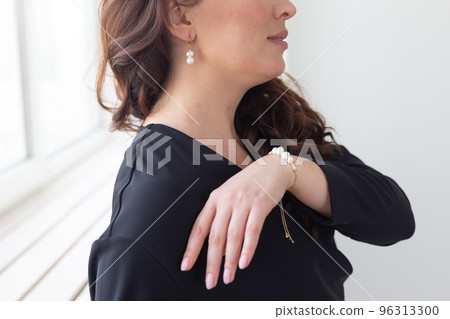 Close-up of woman wearing pearl bracelet and earrings. Jewelry, bijouterie and accessories concept Close-up of woman wearing pearl bracelet and earrings. Jewelry, bijouterie and accessories concept 96313300