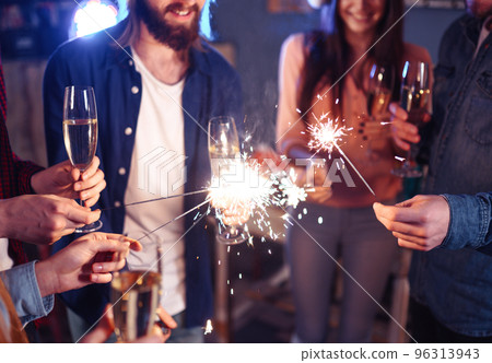 Group of happy people holding sparklers at party. Young people celebrating New Year together. Group of happy people holding sparklers at party. Young people celebrating New Year together. 96313943