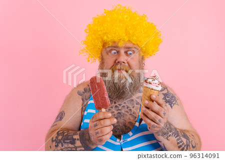 Fat man with beard and wig eats a popsicle and an icecream 96314091
