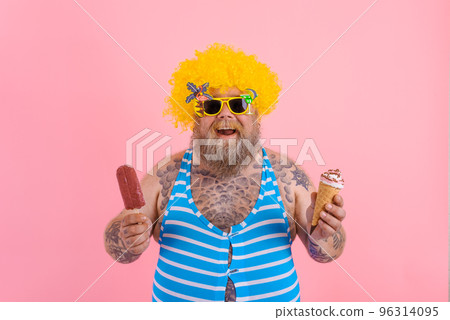 Fat man with beard and wig eats a popsicle and an icecream Fat man with beard and wig eats a popsicle and an icecream 96314095