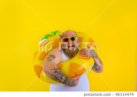 Fat happy man with wig in head is ready to swim with a donut lifesaver Fat happy man with wig in head is ready to swim with a donut lifesaver 96314474