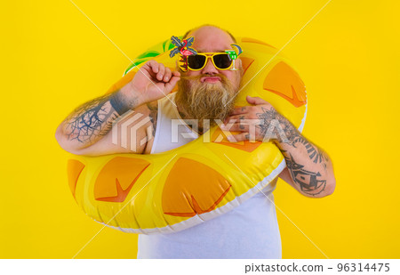 Fat thoughtful man with wig in head is ready to swim with a donut lifesaver Fat thoughtful man with wig in head is ready to swim with a donut lifesaver 96314475