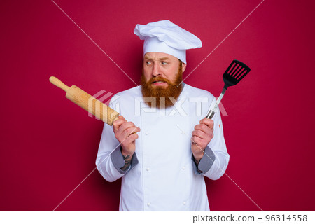 doubter chef with beard and red apron chef holds wooden rolling pin doubter chef with beard and red apron chef holds wooden rolling pin 96314558