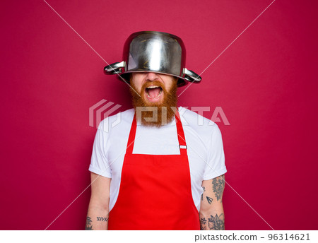 Happy chef with beard and red apron plays with pot 96314621