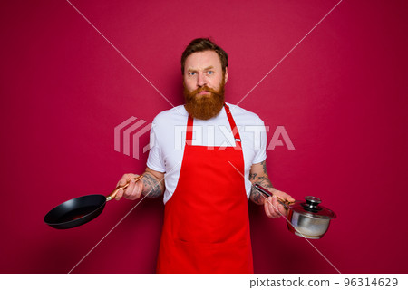 doubter chef with beard and red apron cooks with pan and pot 96314629