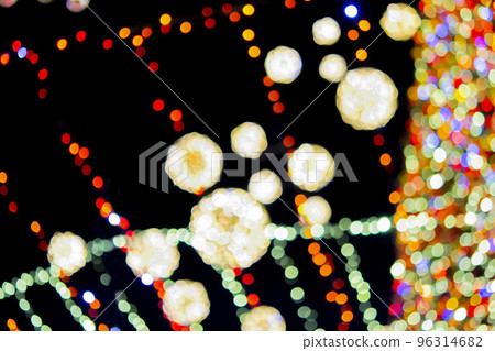 Blurred background. Beautiful luminous and flashing New Year and Christmas decoration garlands and glowing balls for Christmas tree hanging outdoors at black night.Blurry blinking bokeh spots backdrop Blurred background. Beautiful luminous and flashing New Year and Christmas decoration garlands and glowing balls for Christmas tree hanging outdoors at black night.Blurry blinking bokeh spots backdrop 96314682