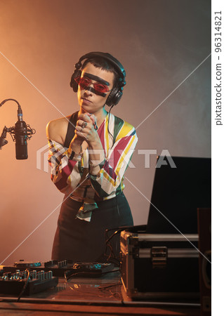 Disc jockey doing prayer hands symbol and begging for hope and fortune, praying and asking for luck at mixing show. Preparing to use turntables to produce music, expressing faith. 96314821